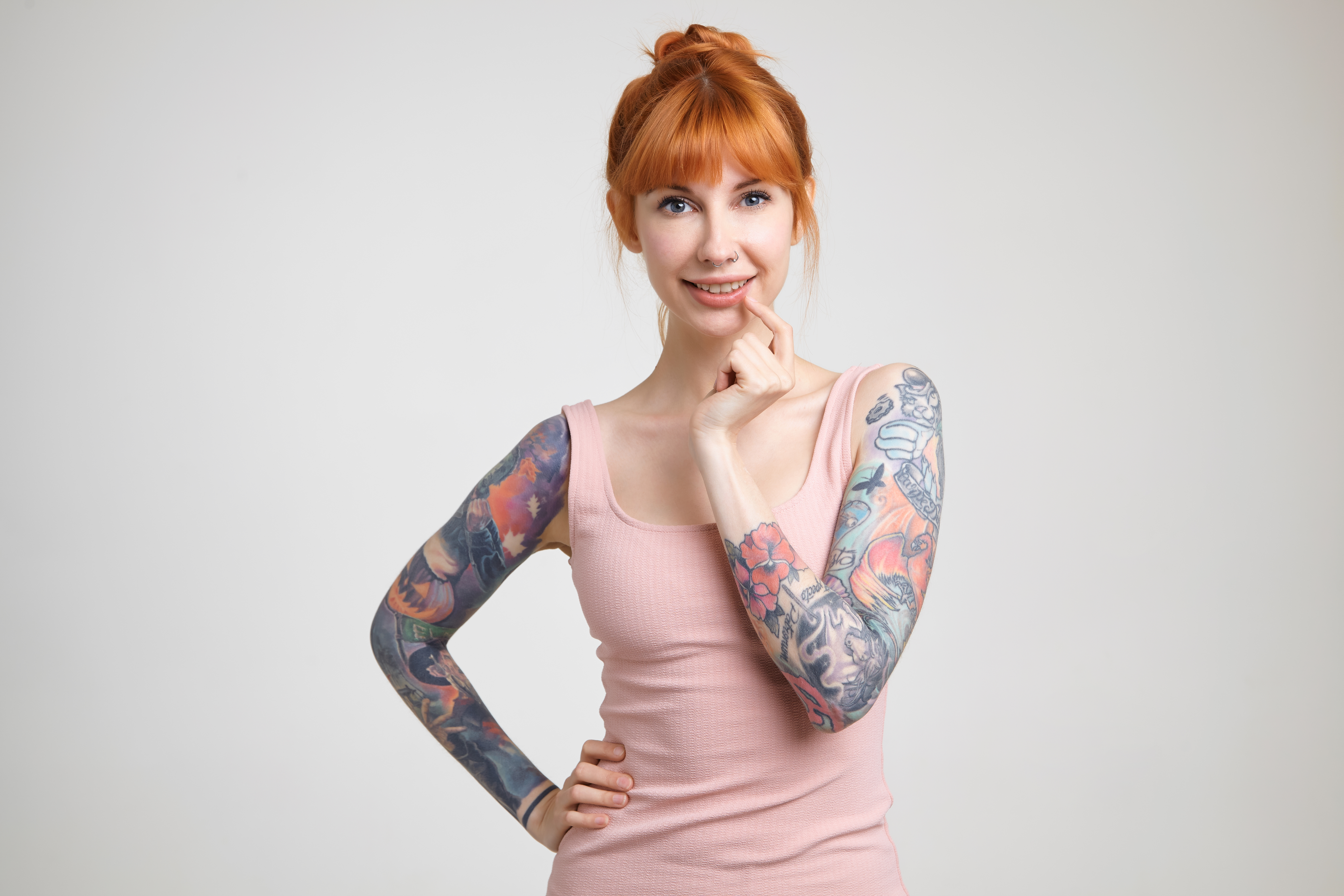 cheerful-young-lovely-redhead-tattooed-lady-with-nose-piercing-looking-positively-camera-with-charming-smile-standing-against-white-background-nude-shirt.jpg